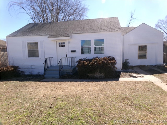 view of front facade featuring a front lawn and roof with shingles