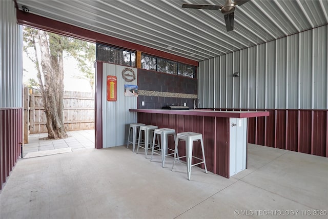 bar with a ceiling fan, concrete floors, and metal wall