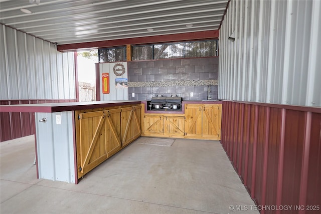 bar with concrete floors, a sink, and backsplash