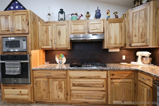 kitchen featuring under cabinet range hood, tasteful backsplash, appliances with stainless steel finishes, and light stone counters