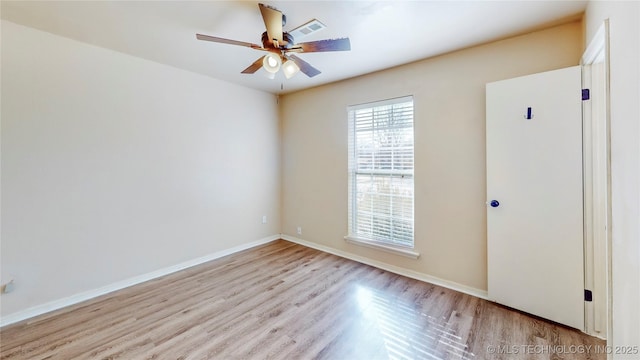 empty room featuring ceiling fan, light wood-style floors, visible vents, and baseboards