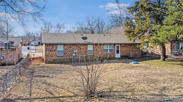 view of front facade with brick siding, a shingled roof, and fence