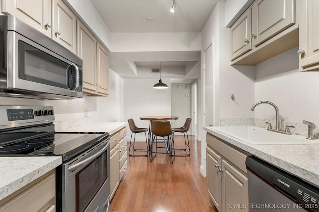 kitchen with a sink, pendant lighting, stainless steel appliances, and light countertops