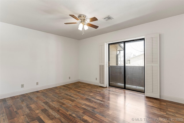 unfurnished room featuring baseboards, visible vents, dark wood finished floors, and a ceiling fan