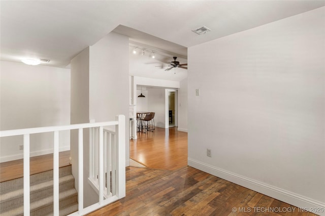 hallway with baseboards, visible vents, wood finished floors, and an upstairs landing