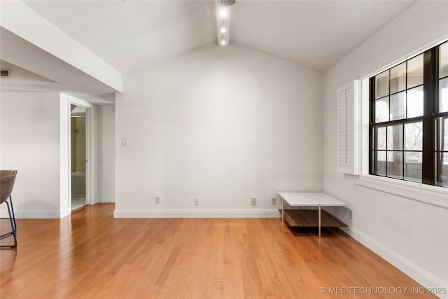 empty room with light wood-type flooring, visible vents, lofted ceiling with beams, and baseboards