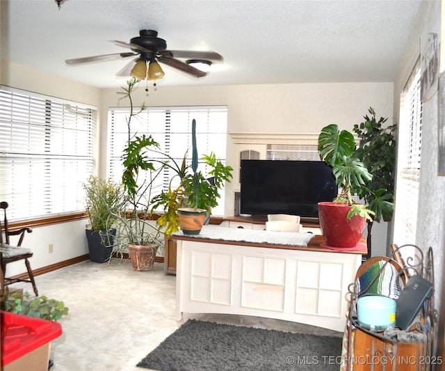 living area featuring ceiling fan and baseboards