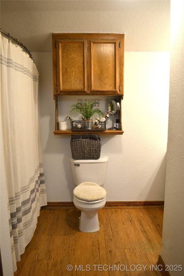 bathroom featuring toilet, a textured ceiling, baseboards, and wood finished floors