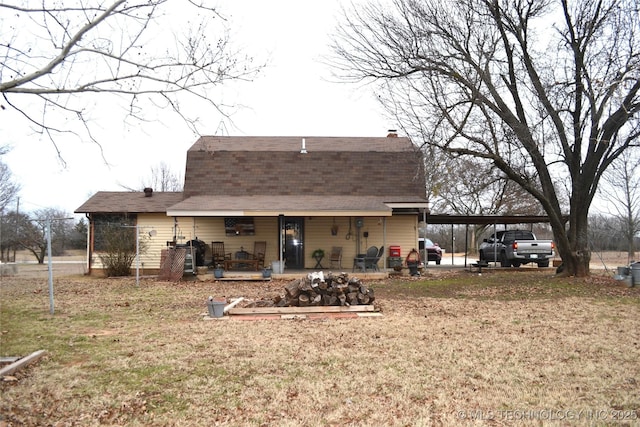 rear view of property with a carport, roof with shingles, a lawn, and a gambrel roof