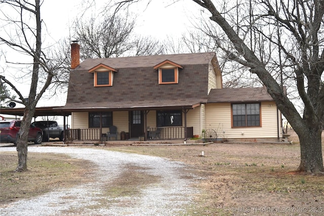 dutch colonial with an attached carport, covered porch, a gambrel roof, driveway, and a chimney