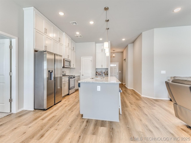 kitchen featuring visible vents, white cabinets, appliances with stainless steel finishes, light stone countertops, and decorative light fixtures