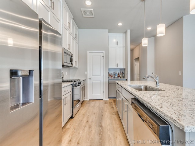 kitchen featuring visible vents, appliances with stainless steel finishes, hanging light fixtures, white cabinetry, and a sink