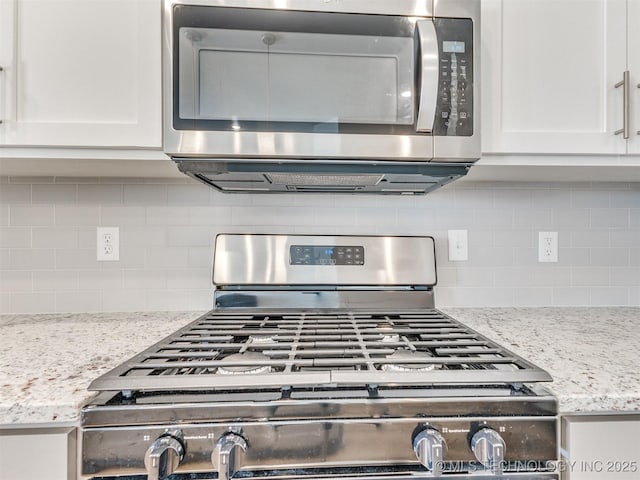 room details with white cabinets, light stone counters, stainless steel appliances, and decorative backsplash