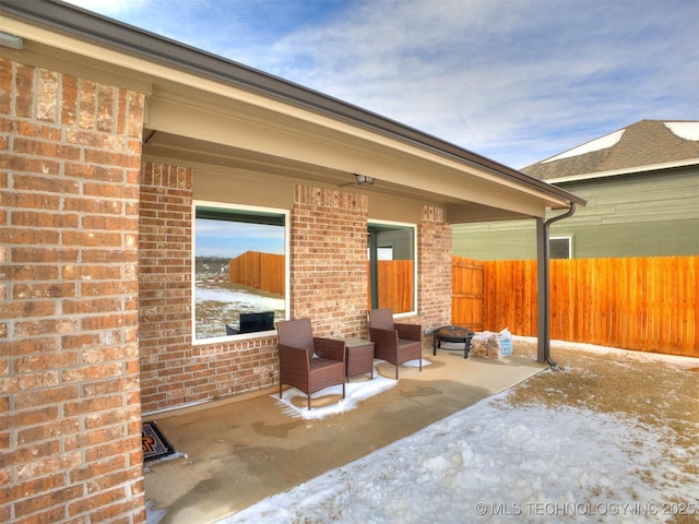 snow covered patio featuring fence private yard and a fire pit