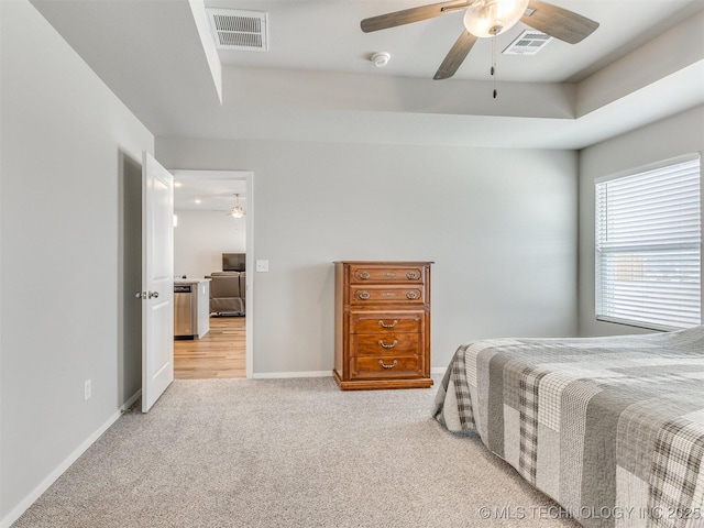 bedroom featuring a raised ceiling, visible vents, and light carpet