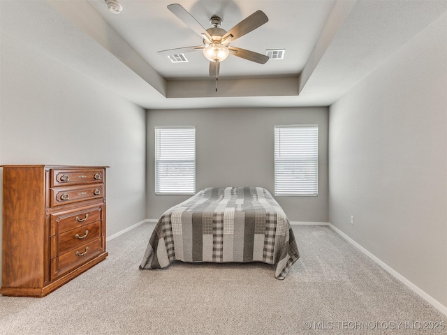 bedroom with a raised ceiling, visible vents, light carpet, and baseboards