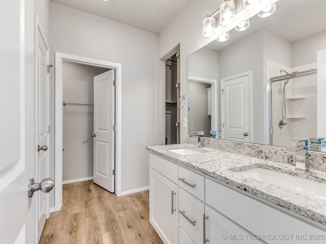 bathroom with wood finished floors, a stall shower, a sink, and baseboards