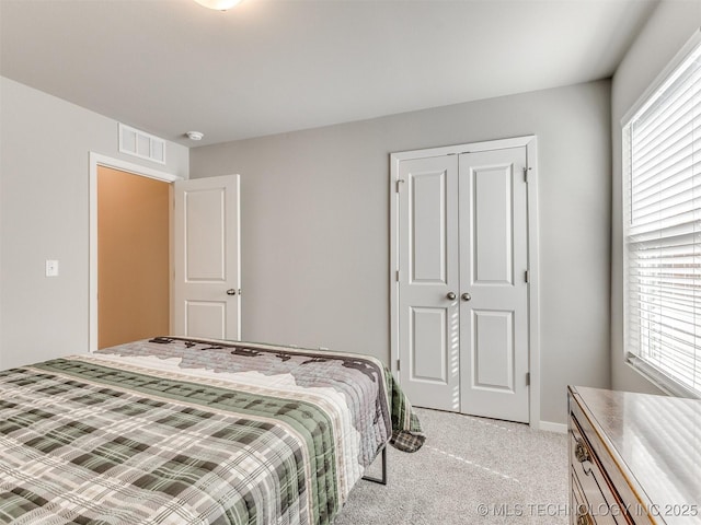 bedroom with visible vents, a closet, and light colored carpet