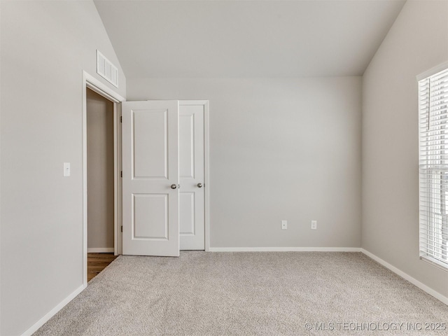 unfurnished bedroom with lofted ceiling, carpet flooring, visible vents, and baseboards