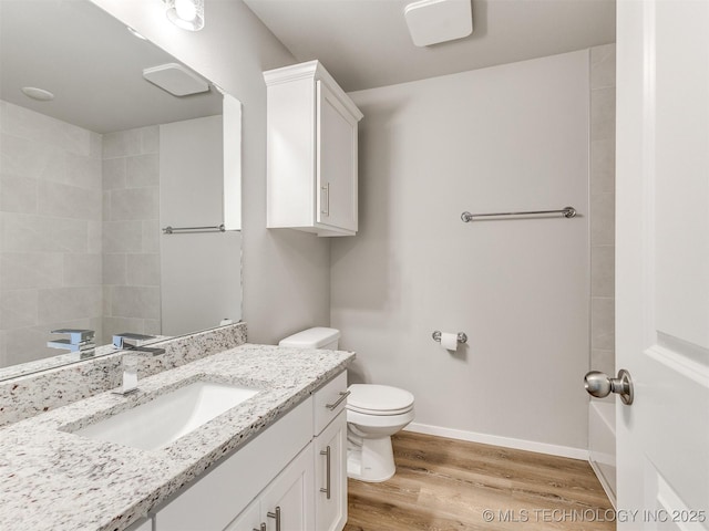 bathroom featuring toilet, baseboards, wood finished floors, and vanity