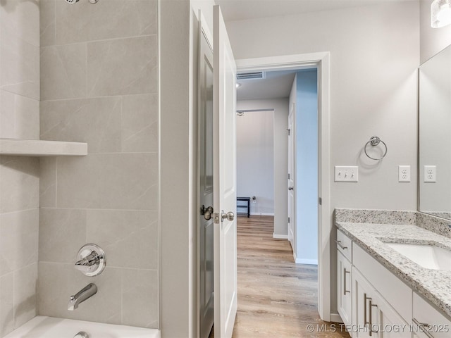 bathroom with visible vents, shower / bath combination, vanity, wood finished floors, and baseboards