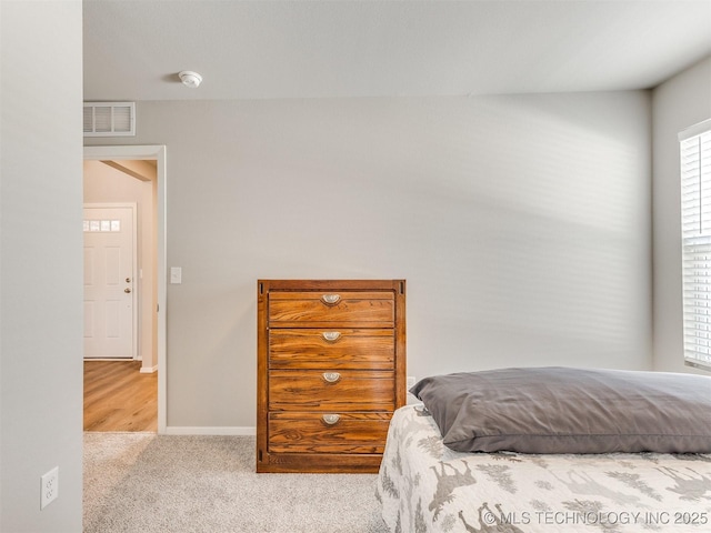 bedroom featuring light carpet, visible vents, and baseboards