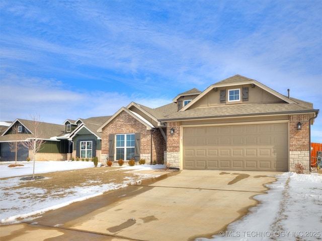 view of front of property featuring a garage, stone siding, brick siding, and roof with shingles