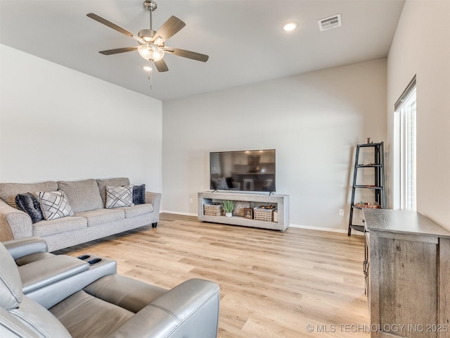 living room with light wood-style floors, visible vents, baseboards, and a ceiling fan