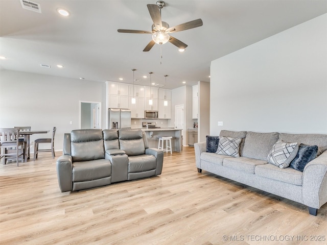 living area with light wood-style floors, ceiling fan, visible vents, and recessed lighting