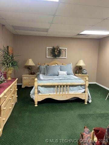 bedroom featuring baseboards, dark carpet, and a drop ceiling