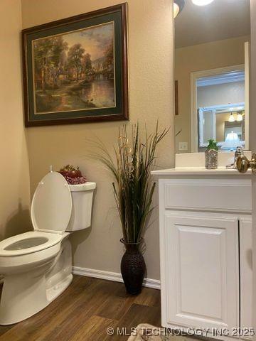 bathroom with baseboards, vanity, toilet, and wood finished floors