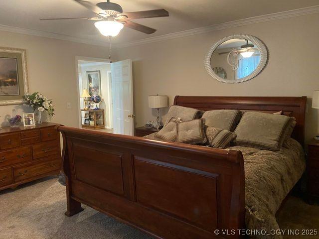 bedroom with ornamental molding, light carpet, and a ceiling fan