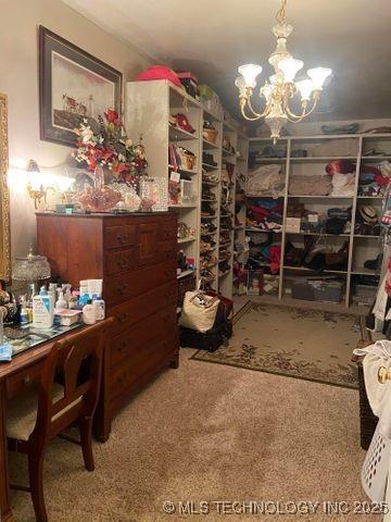 spacious closet featuring carpet floors and an inviting chandelier