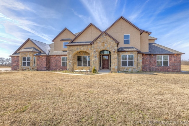 view of front facade featuring a front lawn, brick siding, and stucco siding