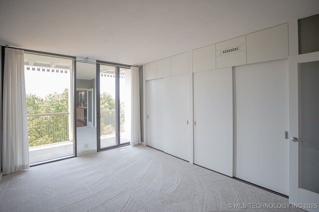 interior space featuring access to outside, floor to ceiling windows, multiple closets, and light colored carpet