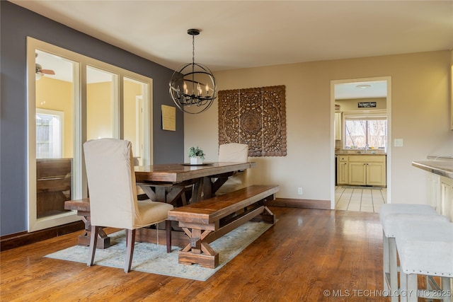 dining space with an inviting chandelier, light wood-style flooring, and baseboards