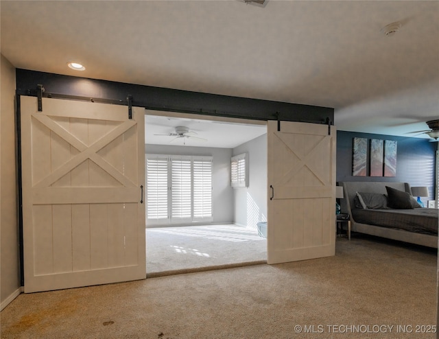 interior space featuring carpet, a barn door, baseboards, and a ceiling fan