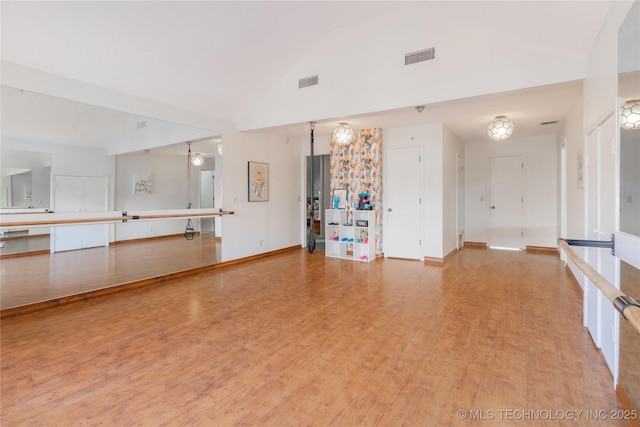 unfurnished living room with high vaulted ceiling, baseboards, visible vents, and wood finished floors