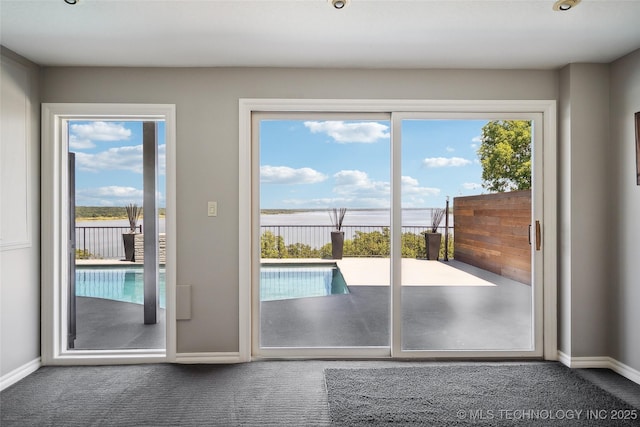 doorway featuring dark carpet and baseboards