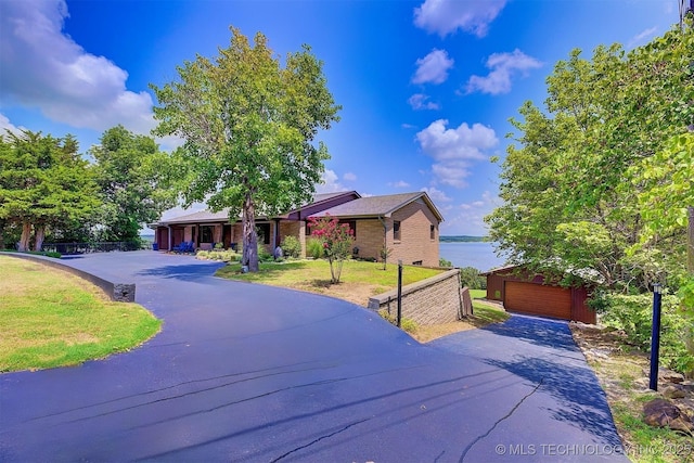 view of front of home featuring a garage, brick siding, and a front lawn