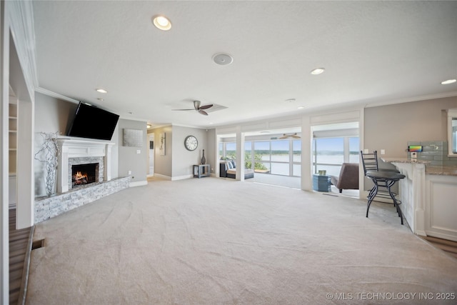 living area featuring light carpet, a fireplace, a ceiling fan, and crown molding