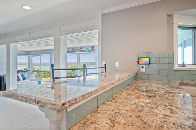 kitchen with a healthy amount of sunlight, ornamental molding, light countertops, and decorative backsplash