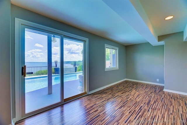 empty room featuring a water view, wood finished floors, and baseboards