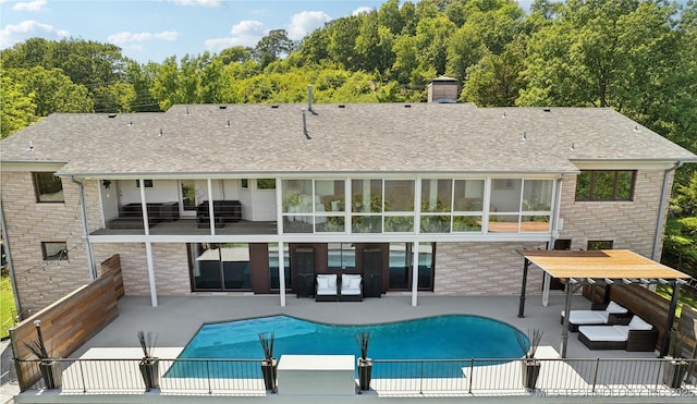 rear view of house with a patio area, outdoor lounge area, a fenced in pool, and roof with shingles