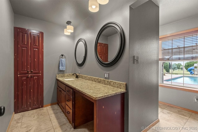 bathroom with tile patterned flooring, baseboards, and vanity