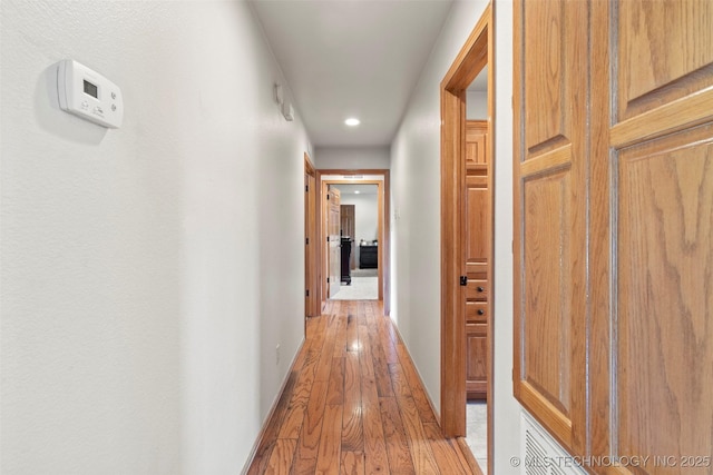 corridor featuring light wood-style floors and baseboards