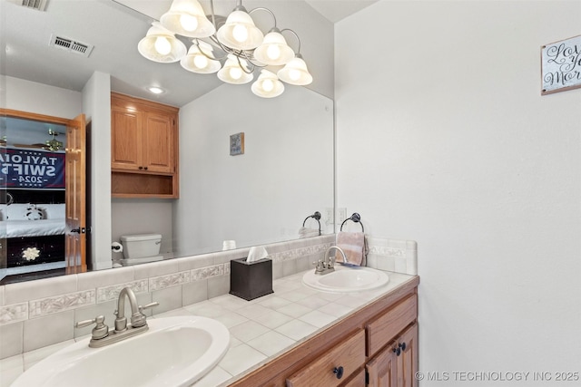 ensuite bathroom featuring toilet, ensuite bath, visible vents, and a sink