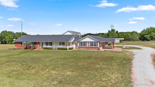 view of front of home with driveway, covered porch, brick siding, and a front yard