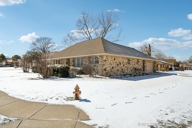 view of snow covered exterior featuring stone siding