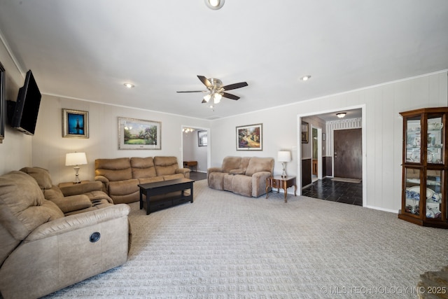 living area featuring crown molding, dark carpet, and ceiling fan